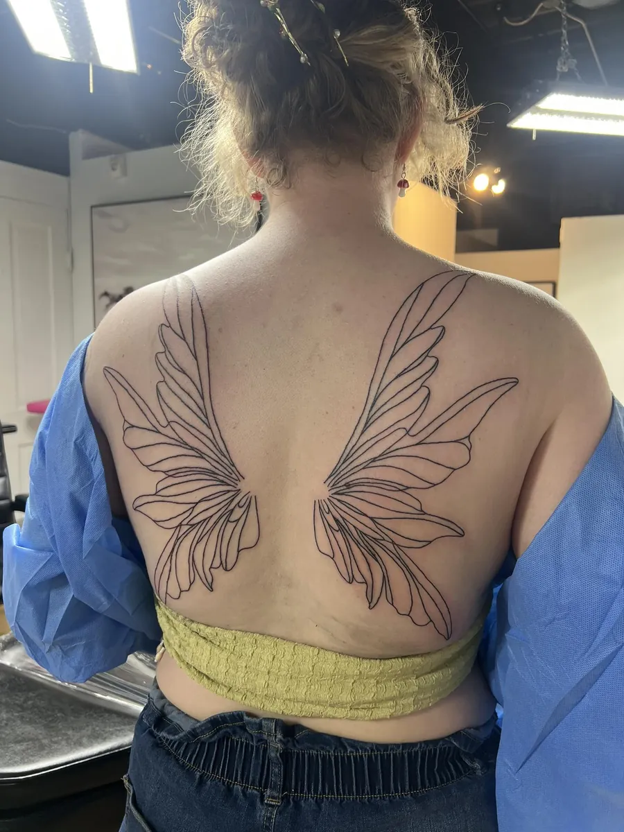 Fairy wings linework spanning the upper back