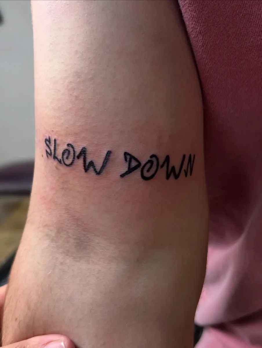 "SLOW DOWN" hand-lettered on the arm