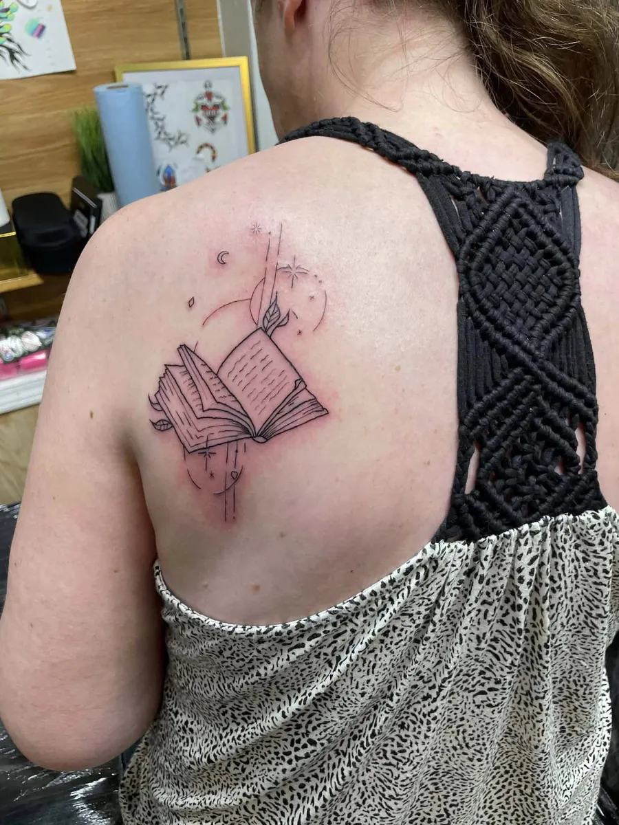 Open spellbook with magic sparkles — fine line on the back